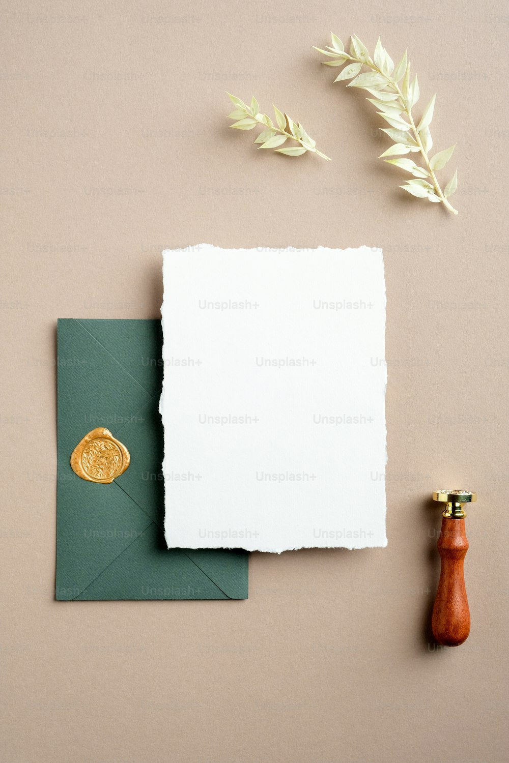 Elegante escena de mockup de papelería de boda. Tarjeta de felicitación en blanco, sobre verde con sello de cera, flores secas sobre fondo beige pastel. Plano, vista superior, vertical.