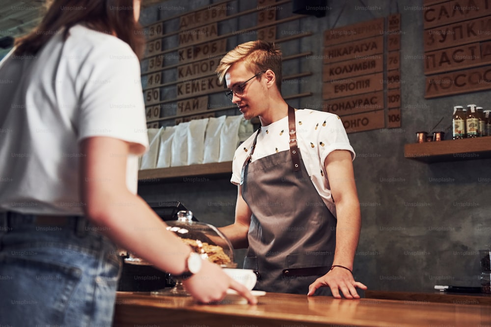 Prozess der Zahlung mit Kreditkarte. Junger männlicher Caféarbeiter drinnen. Konzeption von Geschäft und Service.