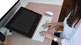 Zugeschnittene Aufnahme einer jungen Grafikdesignerin, die auf einer drahtlosen Tastatur tippt und mit dem Digitizer arbeitet.