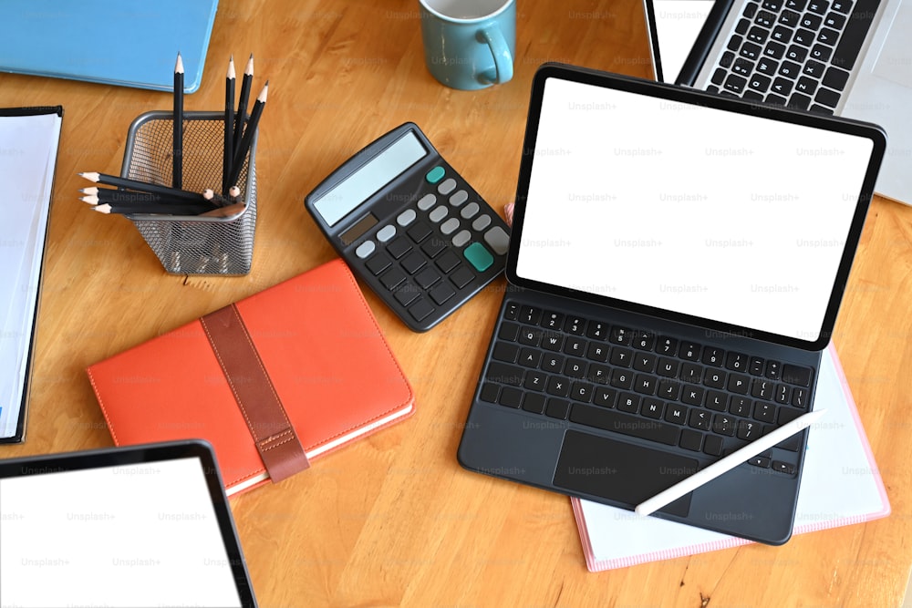 Computador tablet, calculadora, caderno e documento em mesa de escritório de madeira.