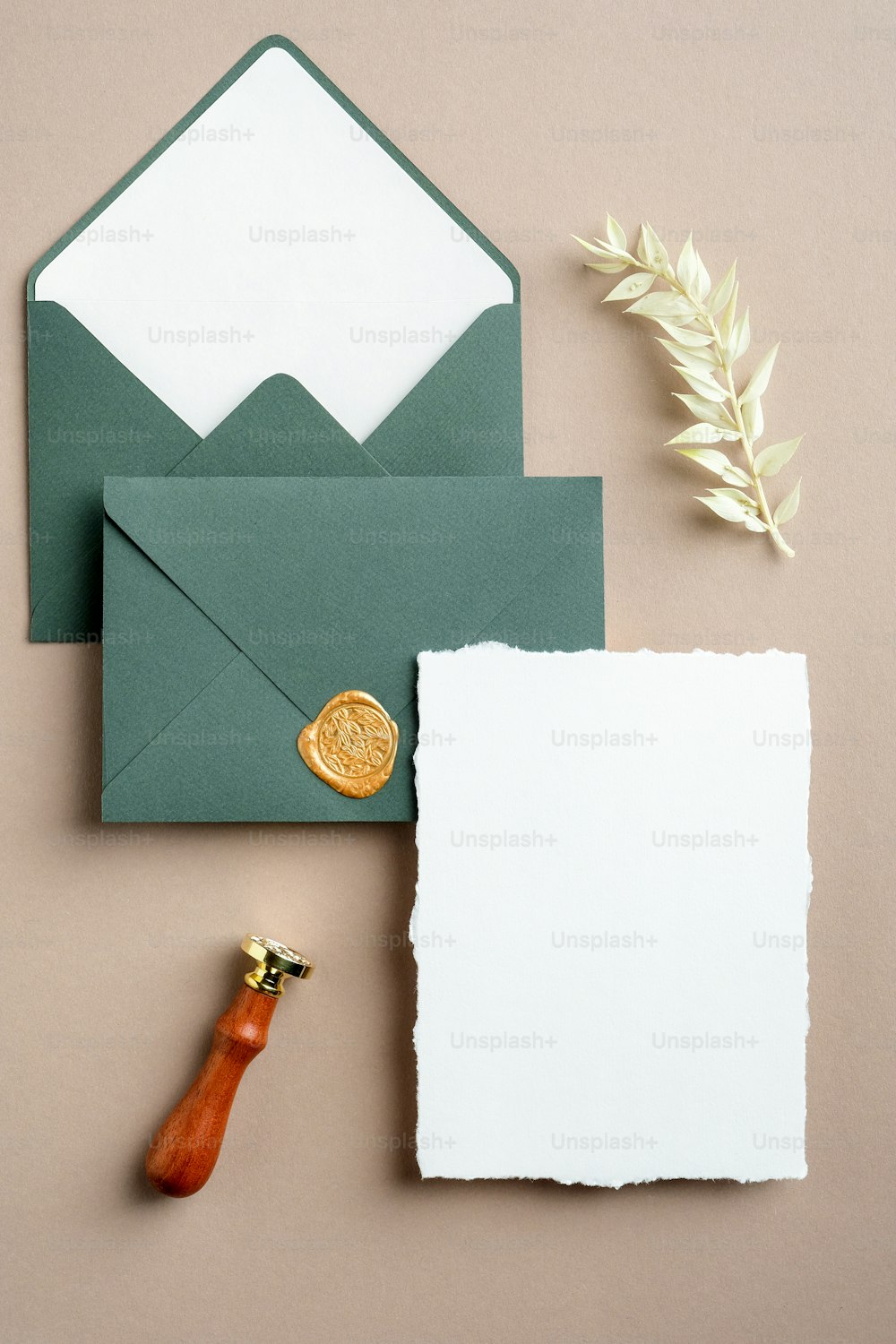 Wedding stationery set top view. Flat lay blank invitation card mockup, green envelopes, wax seal stamp, dried flowers.