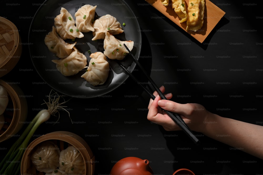 Top view of dinning table in Chinese restaurant, female hand with chopstick picking Dimsum dumplings