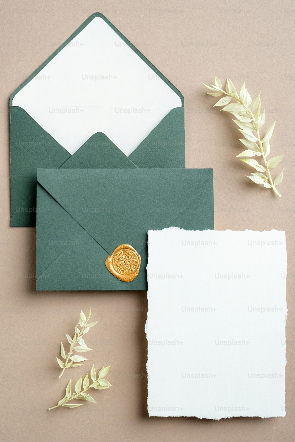 結婚式の詳細招待状テンプレート。パステルベージュの背景にミニマリストのウェディングカードと緑の封筒にドライフラワー。フラットレイ、上面図。