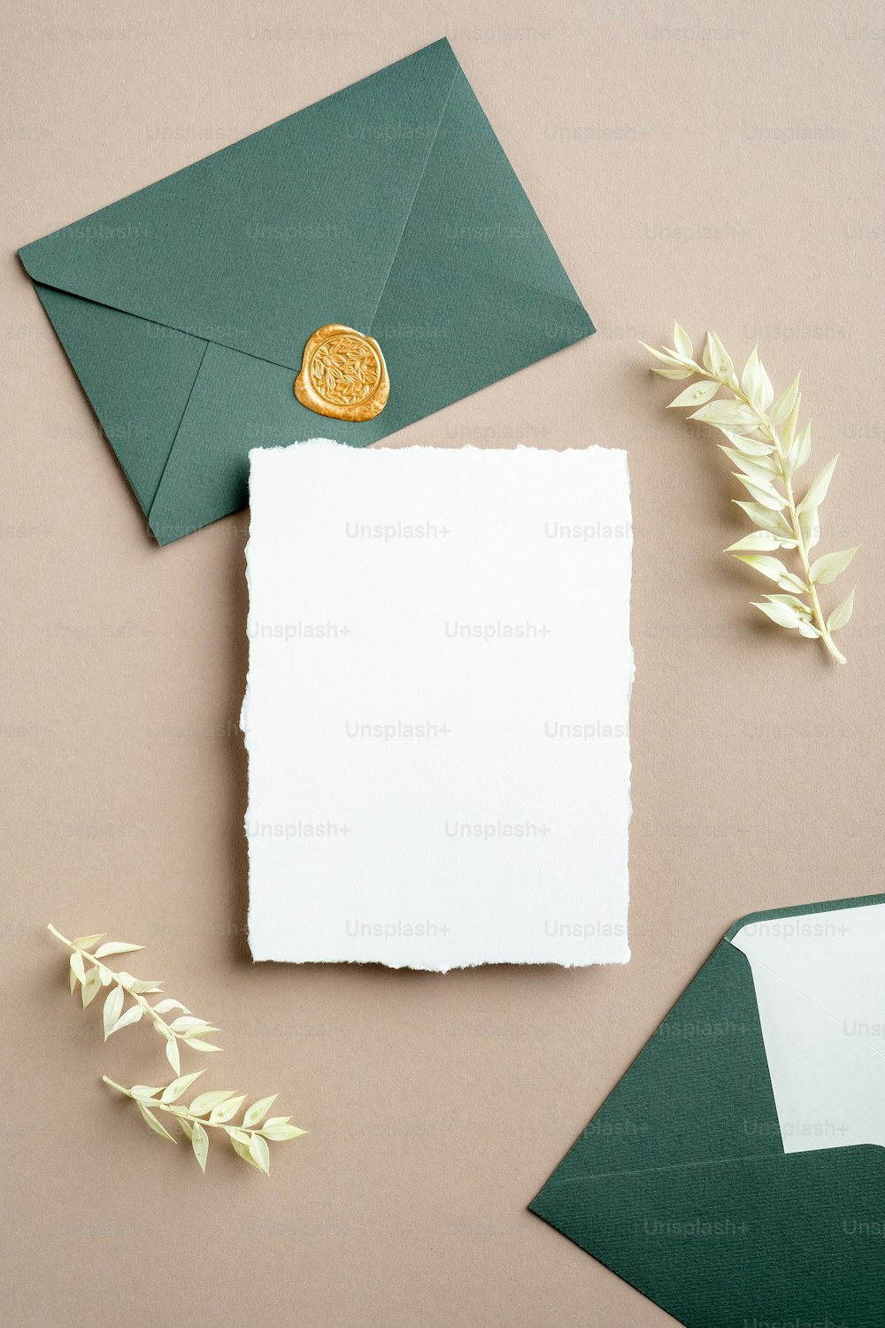 白と緑の結婚式の文房具セット。白紙のグリーティングカード、ワックスシールスタンプ付きのクラフト封筒、ドライフラワー。フラットレイ、上面図、垂直。