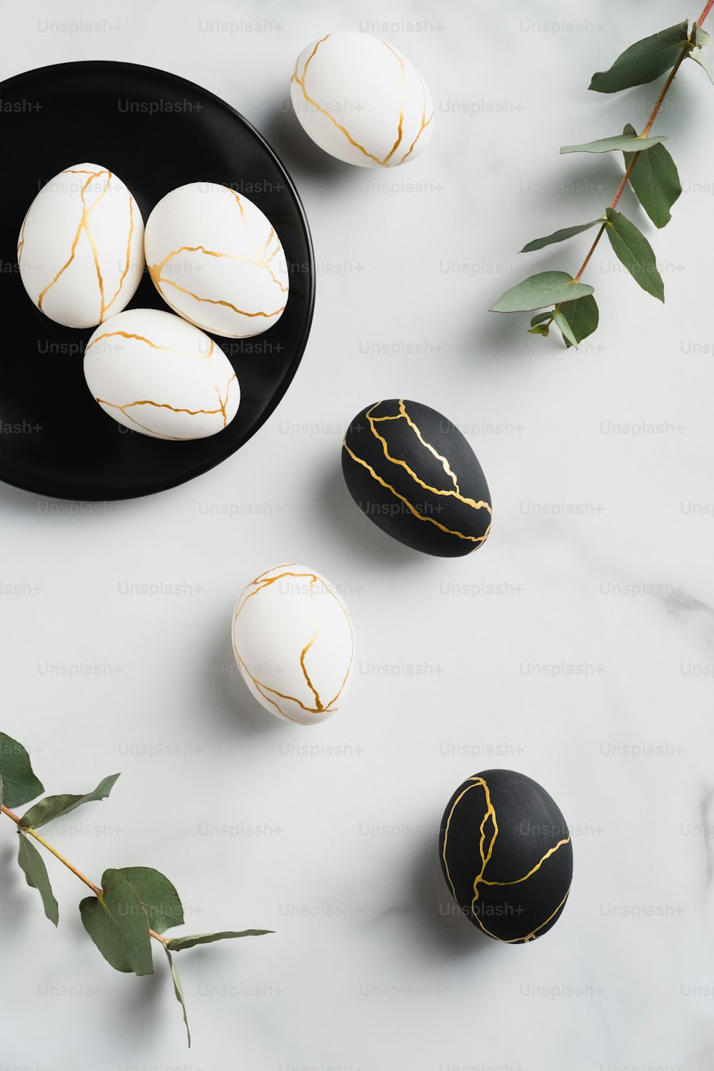 Modern style Easter eggs decorated with golden metal on marble background. Flat lay, top view, vertical