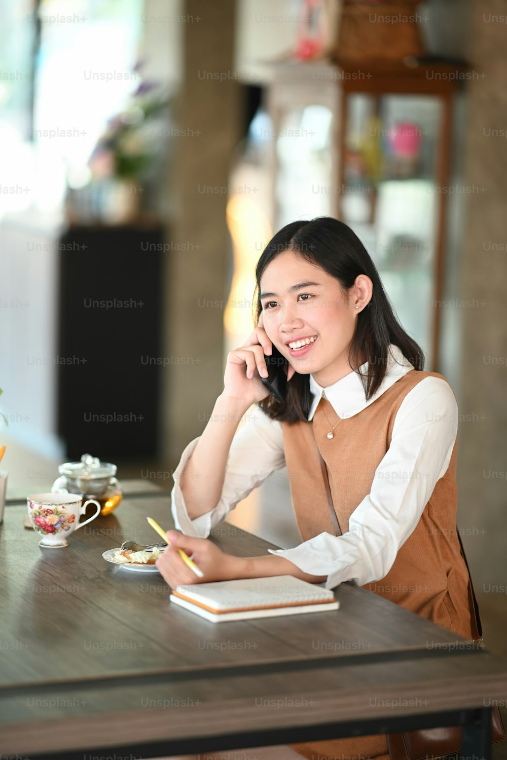 Portrait of young woman talking on mobile phone while sitting in modern cafe.