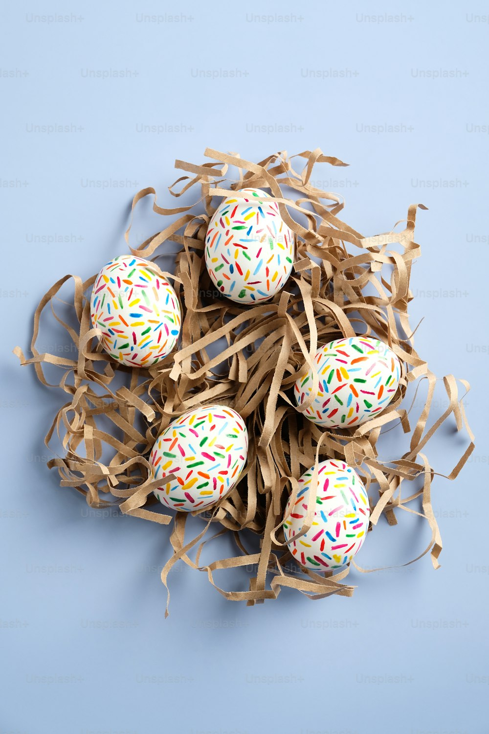 Easter eggs nest on blue background. Flat lay, top view, vertical. Minimal style.