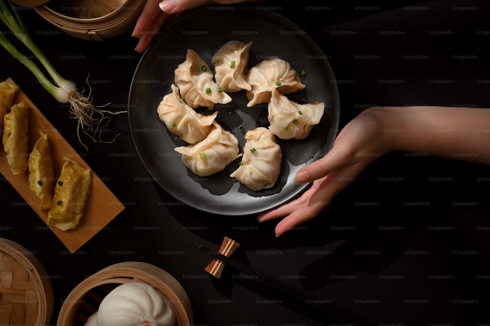 Top view of female hands holding a plate of Dimsum dumplings to place on dining table