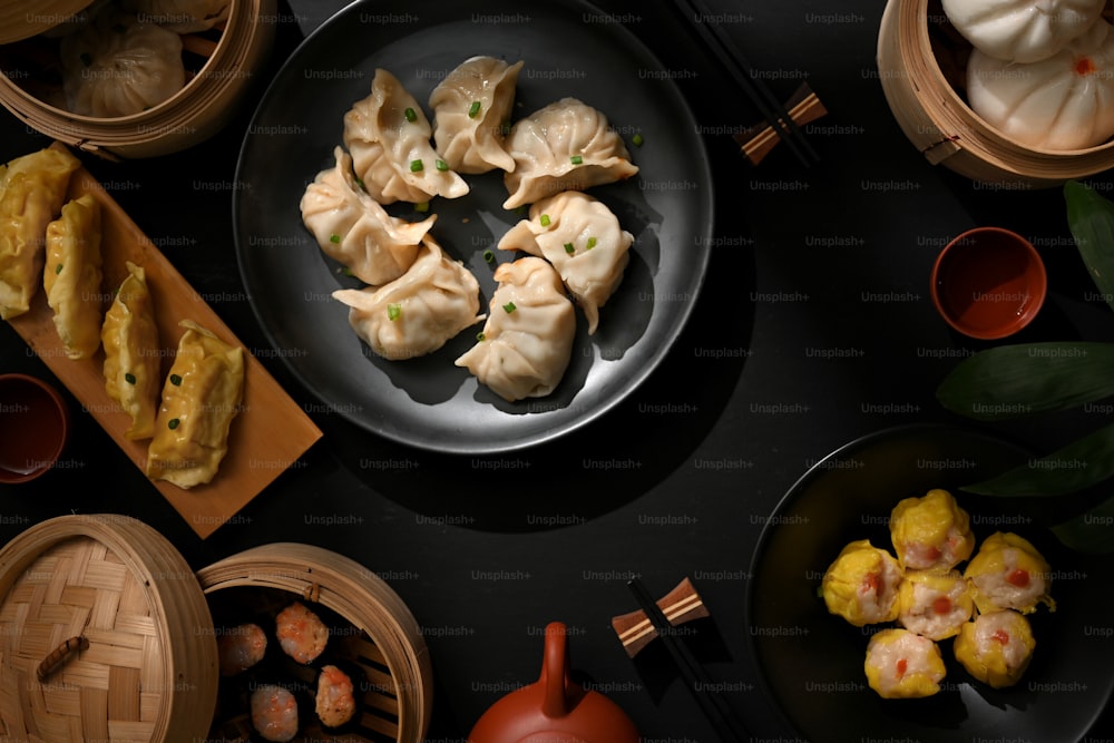 Top view of dinning table in Chinese restaurant with plate and bamboo steamer with dumplings and pork buns