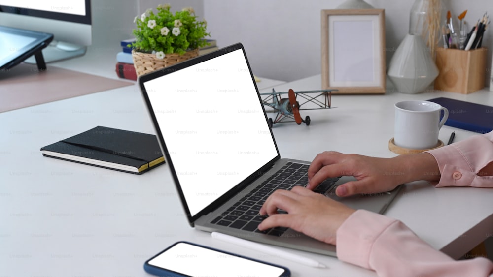Ausschnittaufnahme einer Geschäftsfrau, die am Schreibtisch sitzt und mit einem Laptop arbeitet.