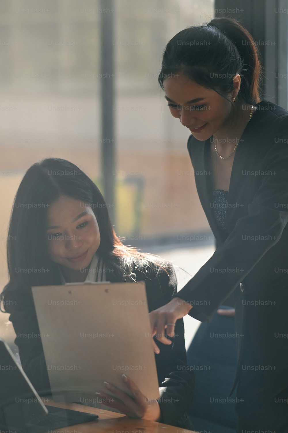 Two young Asian businesswoman discussing business da ta and working together in office.