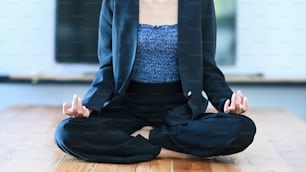 Cropped shot of young businesswoman meditating to relieve stress on the floor in office.