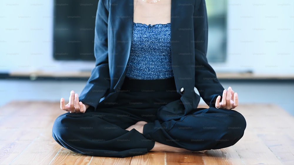 Foto cortada de uma jovem empresária meditando para aliviar o estresse no chão do escritório.