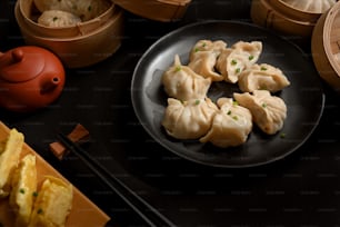 Cropped shot of Dimsum dumplings on black ceramic plate on dinning table in Chinese restaurant