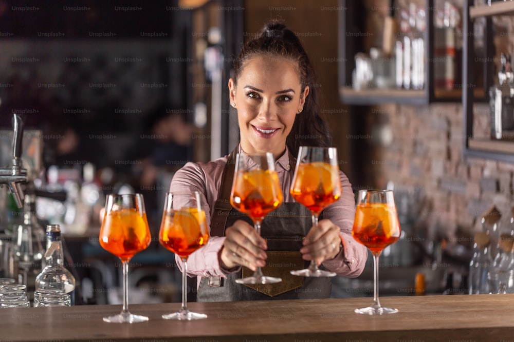 Beautiful waitress offering glasses of freshly-made Spritz cocktail.
