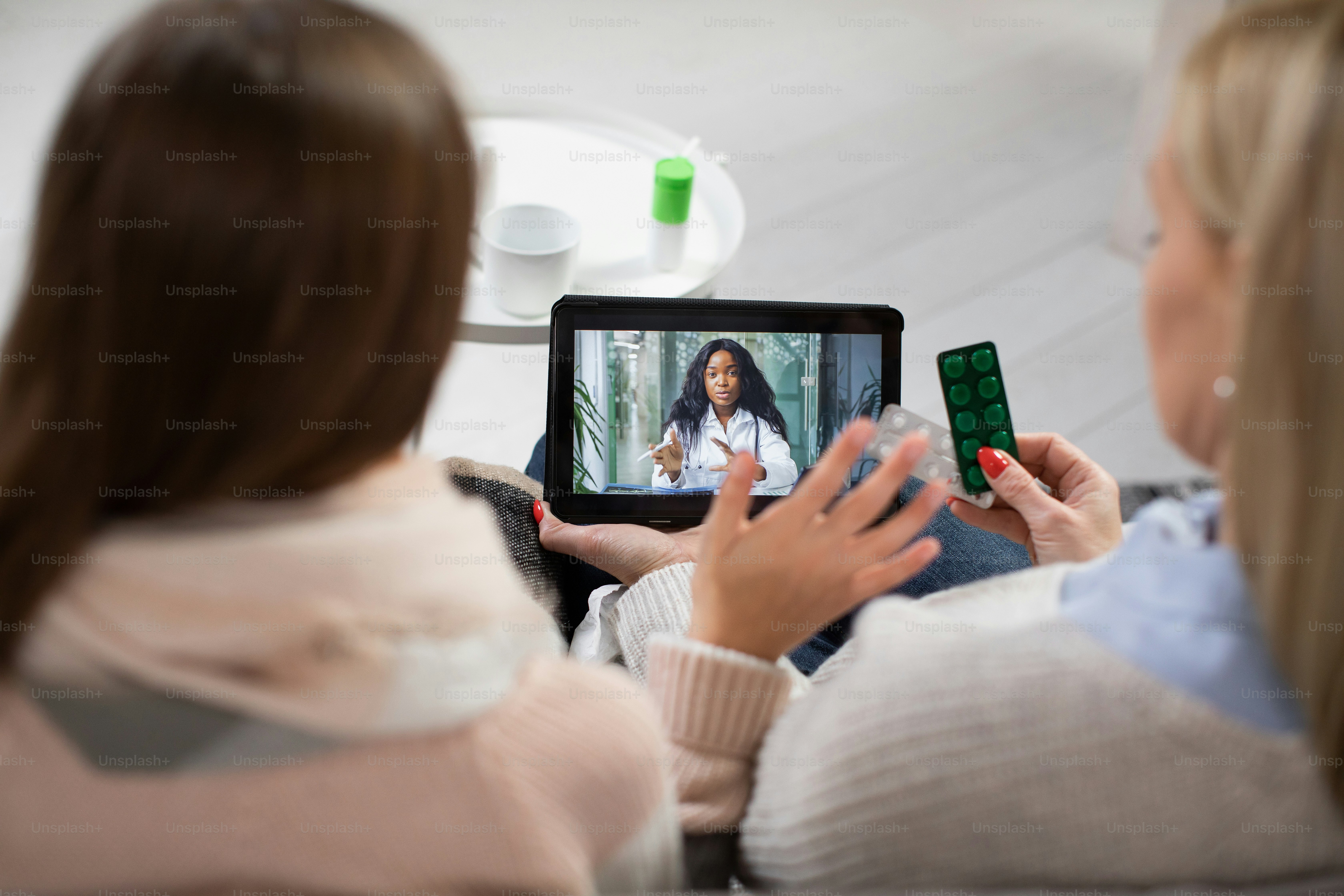 Healthcare concept, online video consultation with doctor. Pretty young African female doctor consulting her patients, Caucasian mother and sick daughter having video call via tablet pc at home.