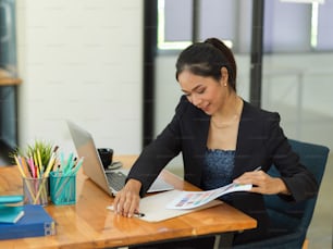 Portrait of businesswoman working with paperwork on wooden table with office supplies in office room