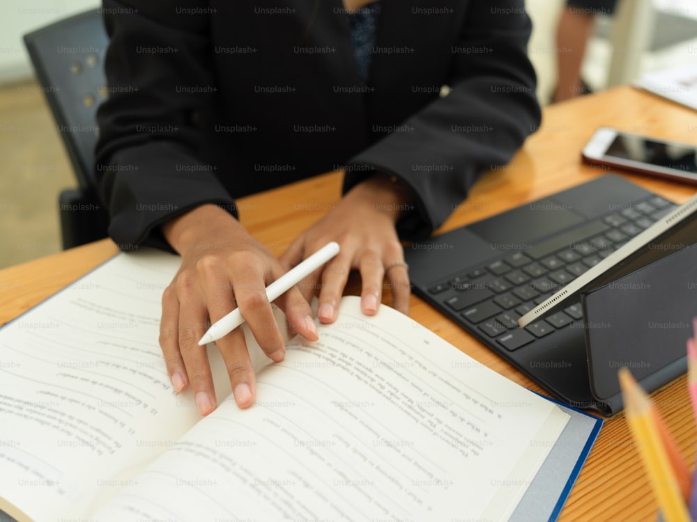 Vista de cerca de una estudiante que se prepara para su próximo examen con libro de texto y tableta digital