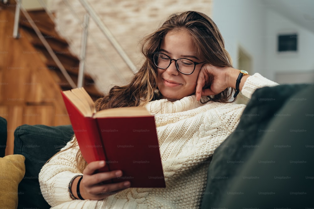 自宅のソファに座って本を読んでいる若い女性のショット