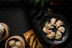 Top view of dinning table in Chinese restaurant with Dimsum on bamboo steamer, dumplings and pork buns