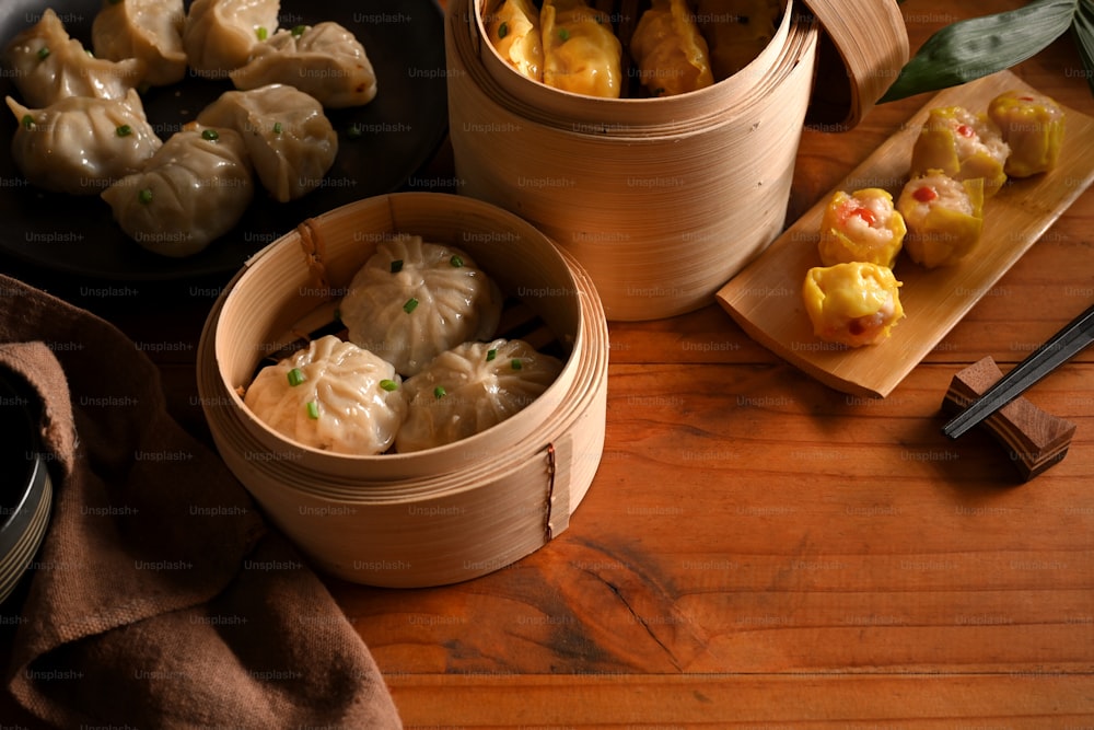 Top view of wooden kitchen table with Dimsum dumplings in bamboo steamers and copy space
