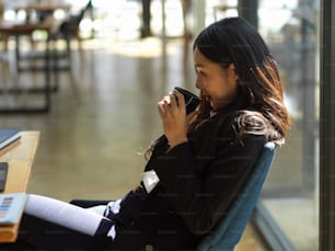Close up view of businesswoman relaxing with coffee while sitting at workspace in co-working space