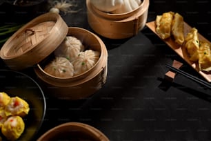 Draufsicht auf den Esstisch im chinesischen Restaurant mit Dinsum-Knödeln auf Bambusdampfer und Essstäbchen