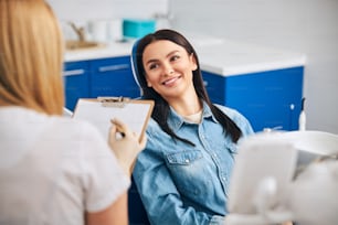 Professional dentist wearing uniform while working in cabinet with patient