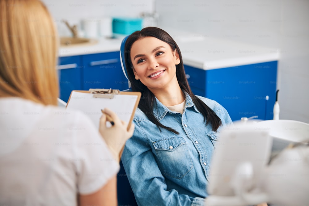 Professional dentist wearing uniform while working in cabinet with patient