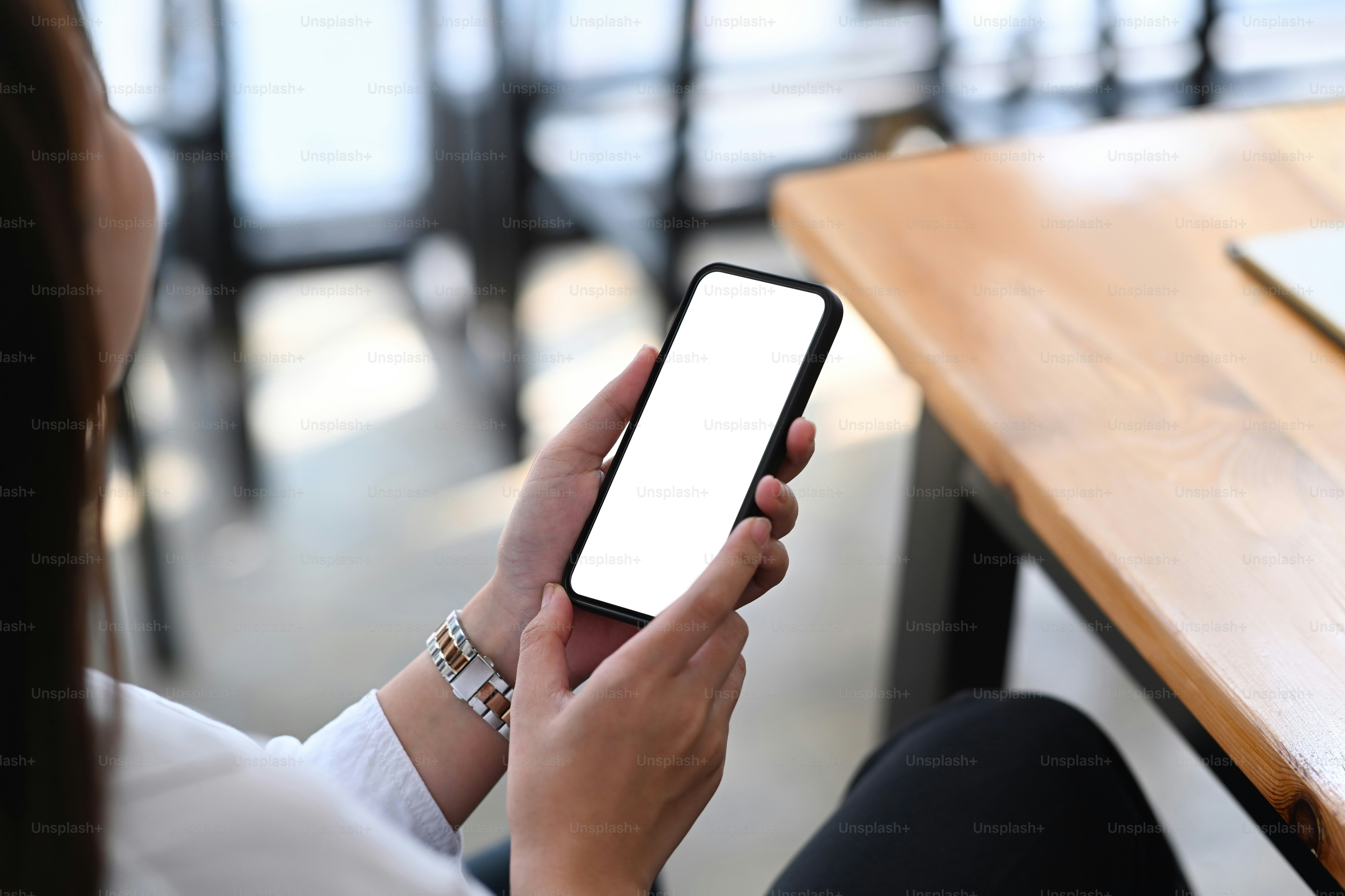 Cropped shot of young female entrepreneur sitting at her workplace and using mobile phone.