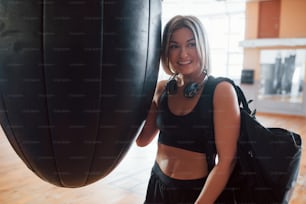 That good feeling after training. Adult female with black bag and headphones in the gym.