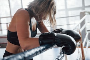 Leaning on the ropes. Tired after workout. Having rest in the gym for box sport training.