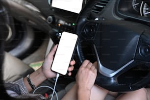 Plan recadré d’une jeune femme connectant un téléphone intelligent au système audio de la voiture à l’aide de la technologie sans fil.