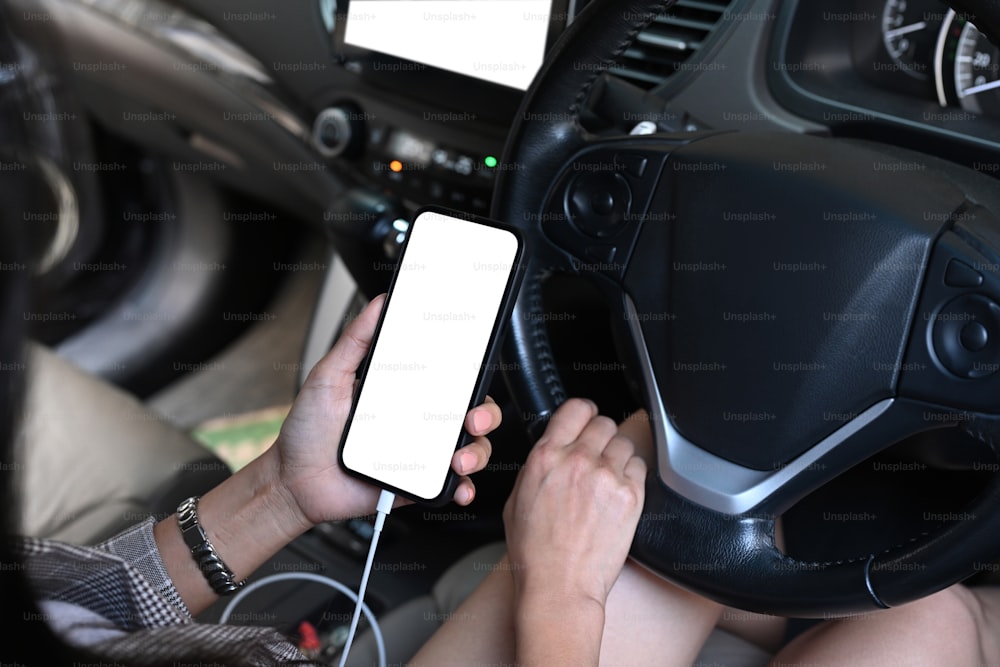 무선 기술을 사용하여 스마트폰을 자동차 오디오 시스템에 연결하는 젊은 여성의 자른 샷.