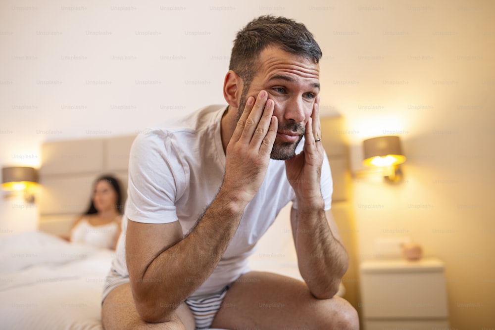 Young couple lying in bed under blanket in bedroom at home, woman in lingerie sleeping, sad, frustrated man thinking about relationships, family having sexual problems, impotence concept close up