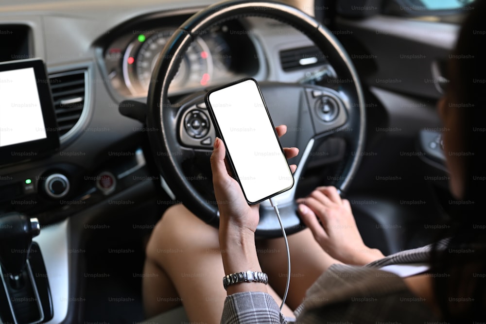 차를 운전하는 동안 스마트 폰 문자 메시지를 사용하거나 메시지를 읽는 젊은 매력적인 여성.
