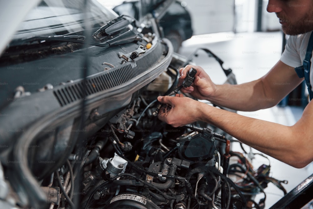 Focused photo. Employee in the blue colored uniform works in the automobile salon.