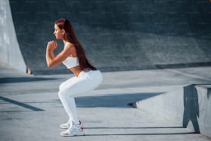 Foto de mulher esportiva fazendo exercícios de fitness perto do lago durante o dia.