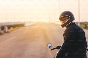Jeune homme conduisant une grosse moto à moto sur l’asphalte à l’encontre de l’homme, un homme à moto a la liberté