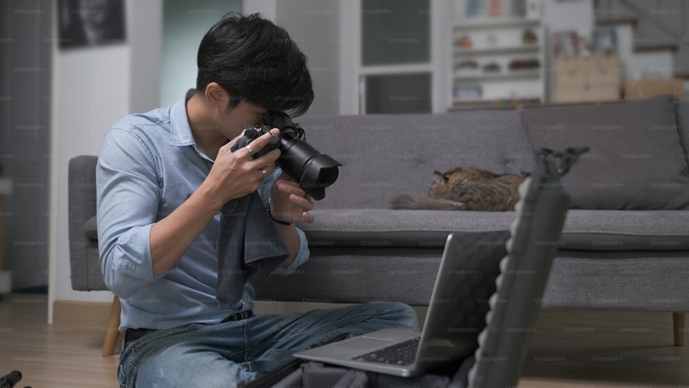 Fotógrafo jovem verificando e ajustando a configuração de sua câmera antes de fotografar.