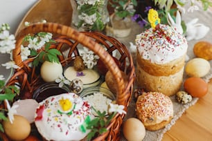 Cibo tradizionale di Pasqua per la benedizione, pane pasquale fatto in casa, uova di Pasqua eleganti e fiori primaverili che sbocciano su tovagliolo di lino su tavola rustica. Buona Pasqua! Colazione festiva