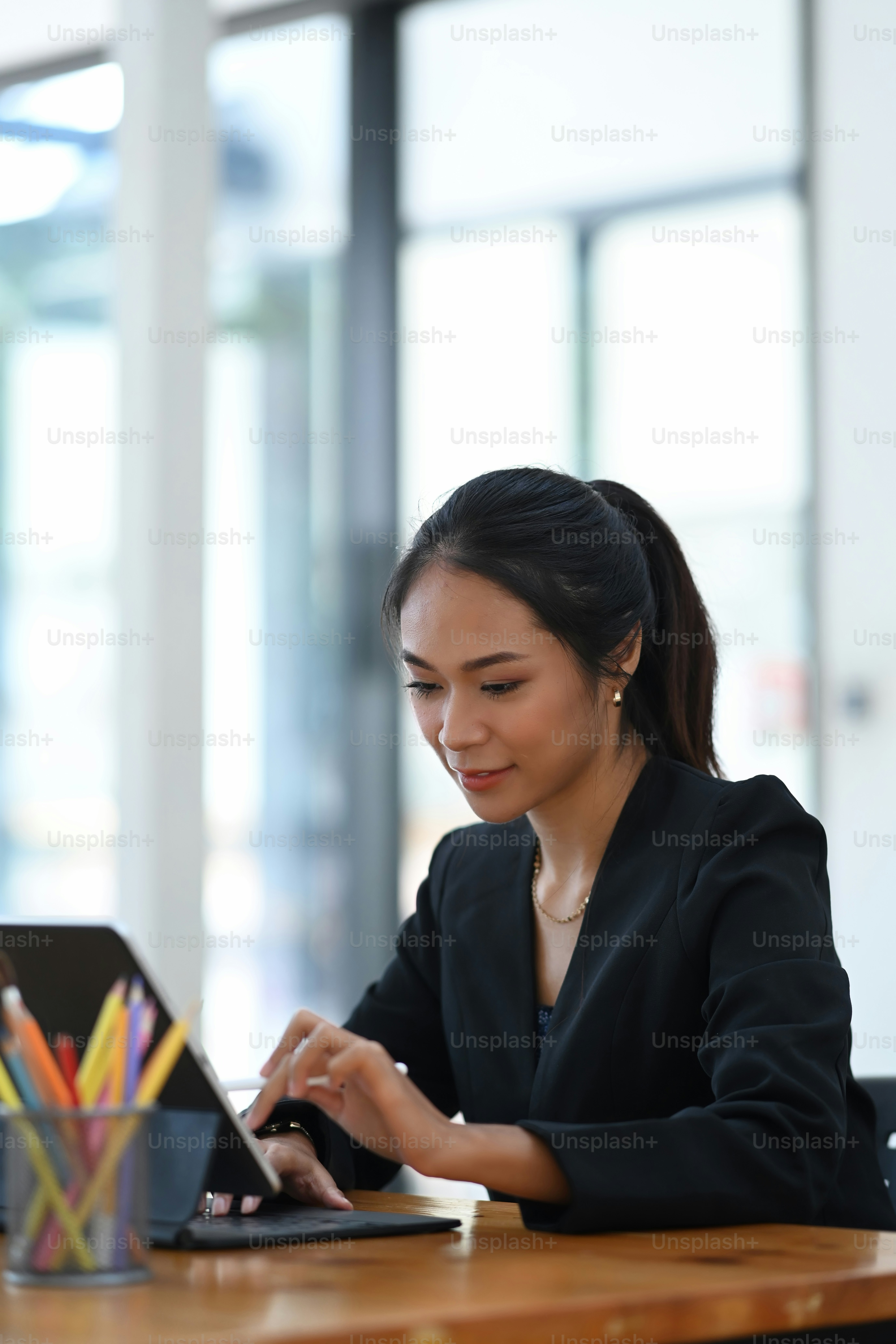 Portrait d’une femme d’affaires attrayante travaillant en ligne avec une tablette d’ordinateur tout en étant assise sur un lieu de travail moderne.