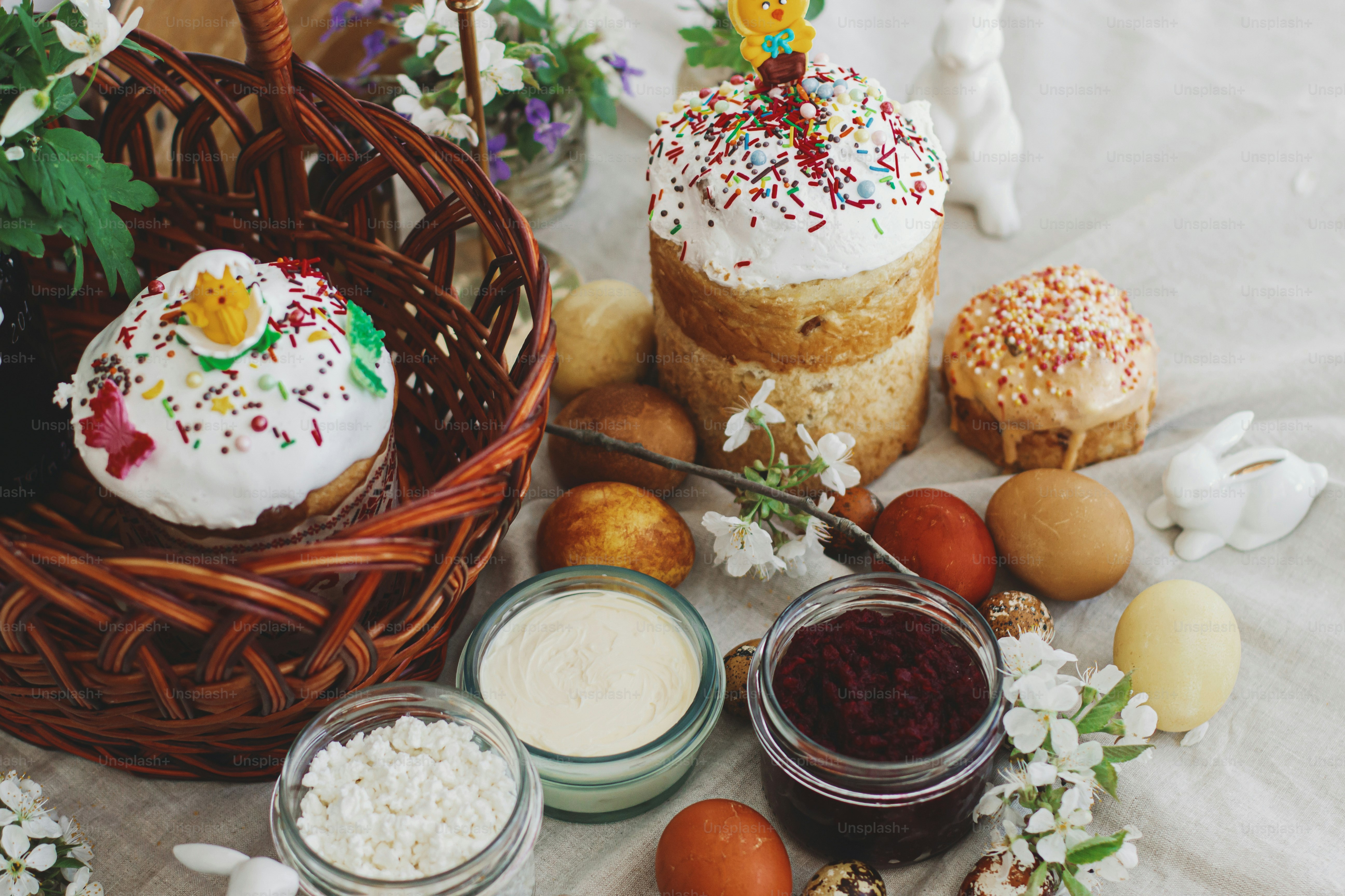 Cibo tradizionale di Pasqua per la benedizione, pane pasquale fatto in casa, uova di Pasqua eleganti e fiori primaverili che sbocciano su tovagliolo di lino su tavola rustica. Buona Pasqua! Colazione festiva