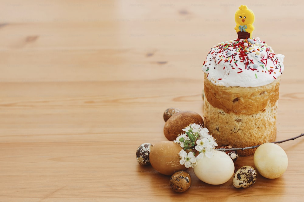 Delicious homemade Easter bread, stylish easter eggs, blooming spring flowers on rustic table. Happy Easter! Space for text. Modern natural dyed eggs and traditional Easter food