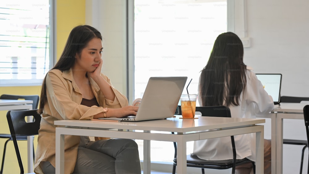 Plan recadré d’une femme d’affaires travaillant avec un ordinateur portable sur la table dans un espace de co-working