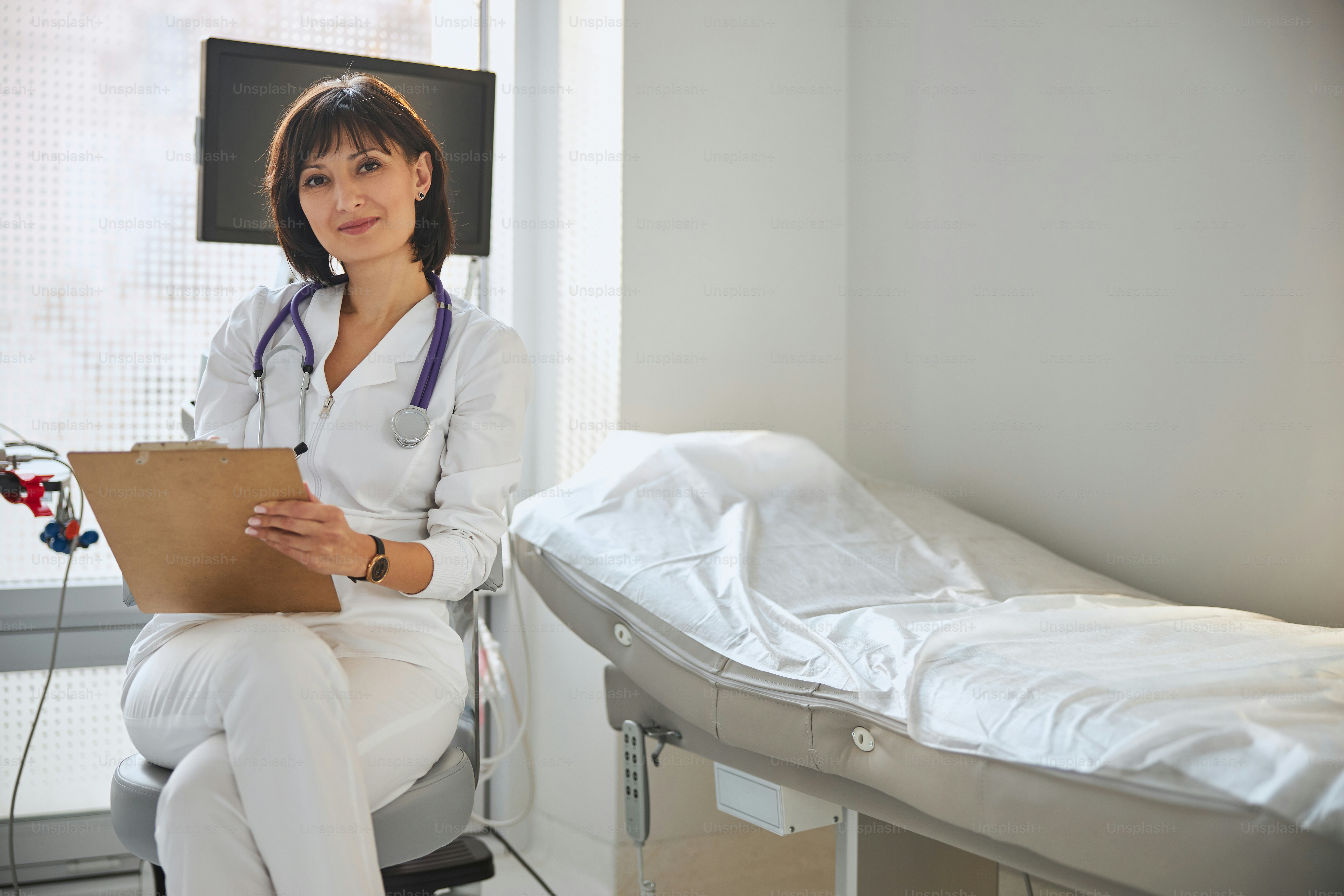 Vue de face d’un médecin d’âge moyen souriant et serein assis sur la chaise de son bureau
