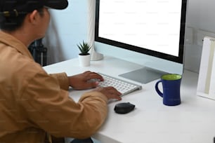 Junger Mann Freelancer konzentriert sich auf die Arbeit am Computer, während er im modernen Home Office sitzt.