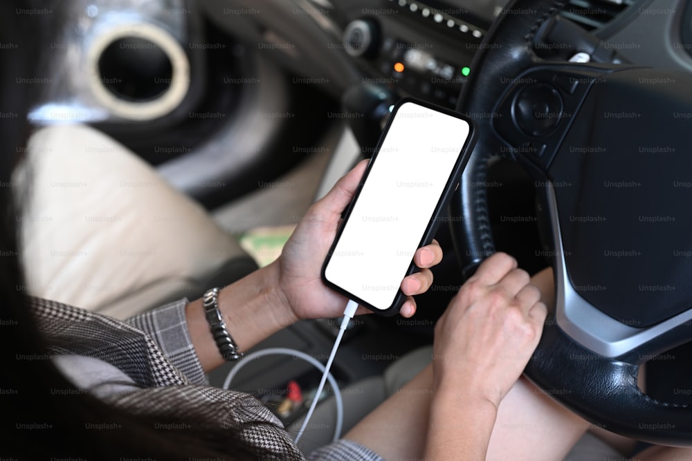 차를 운전하는 동안 스마트폰으로 문자를 보내는 젊은 여성의 모습을 닫습니다.