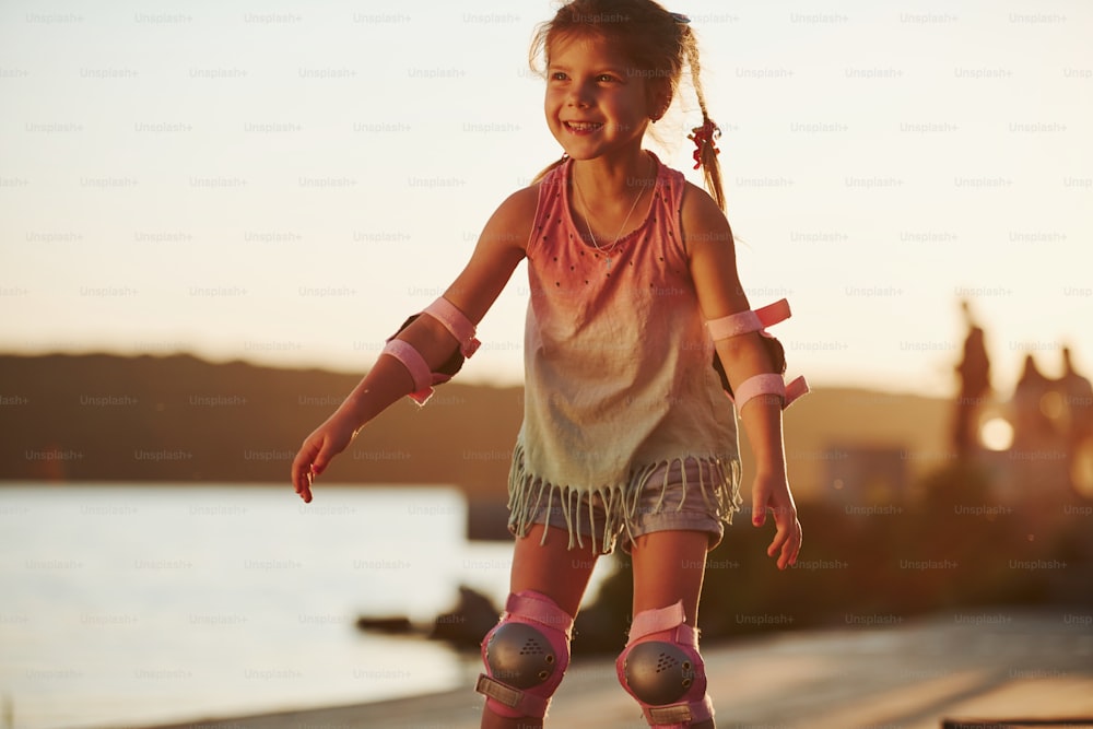 Happy cute kid riding on her roller skates. Unbelievable sunlight.