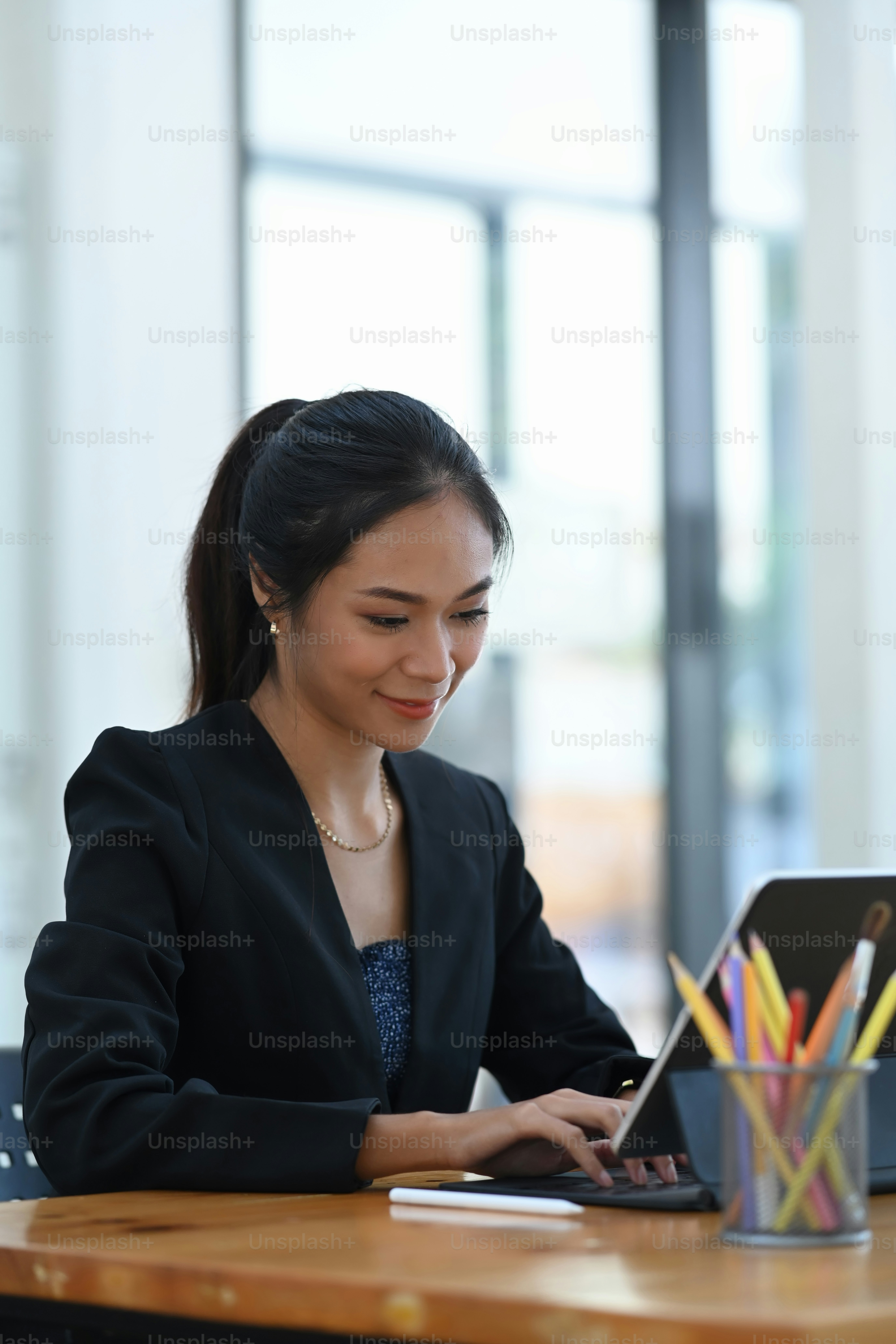 Portrait of happy businesswoman sitting at wooden office desk and working on computer laptop.